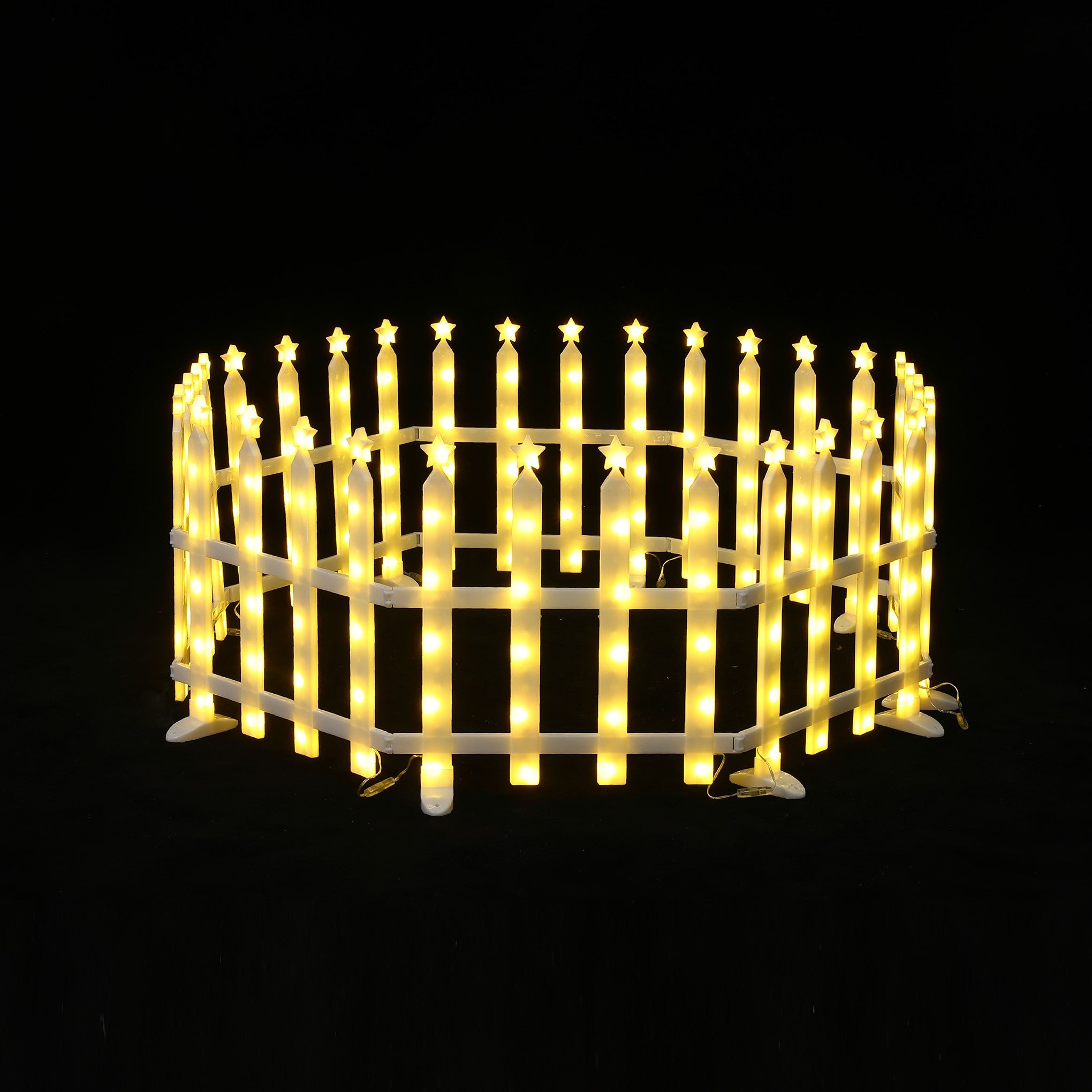 Round, white picket fence is illuminated with yellow star-shaped lights, set against black background.