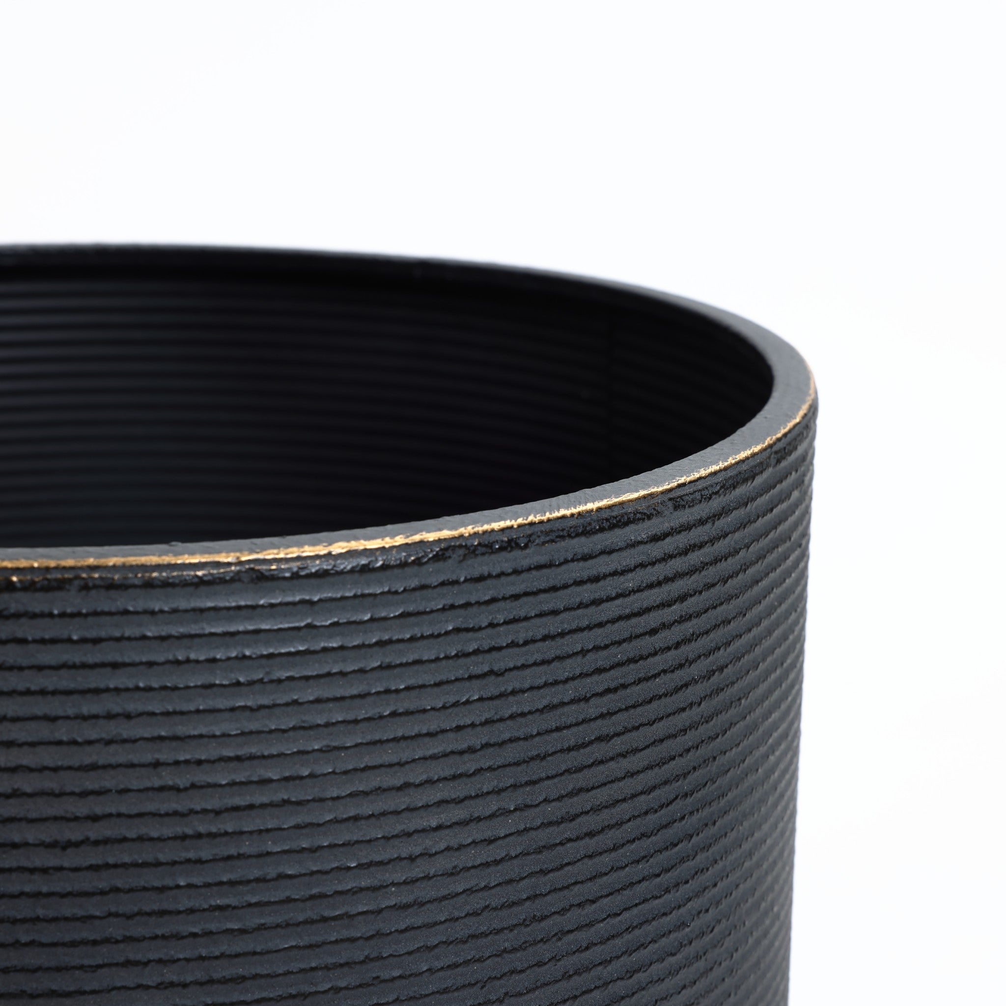 Close-up of a black, textured cylindrical container with a distressed black finish and a slightly worn rim on a white background.