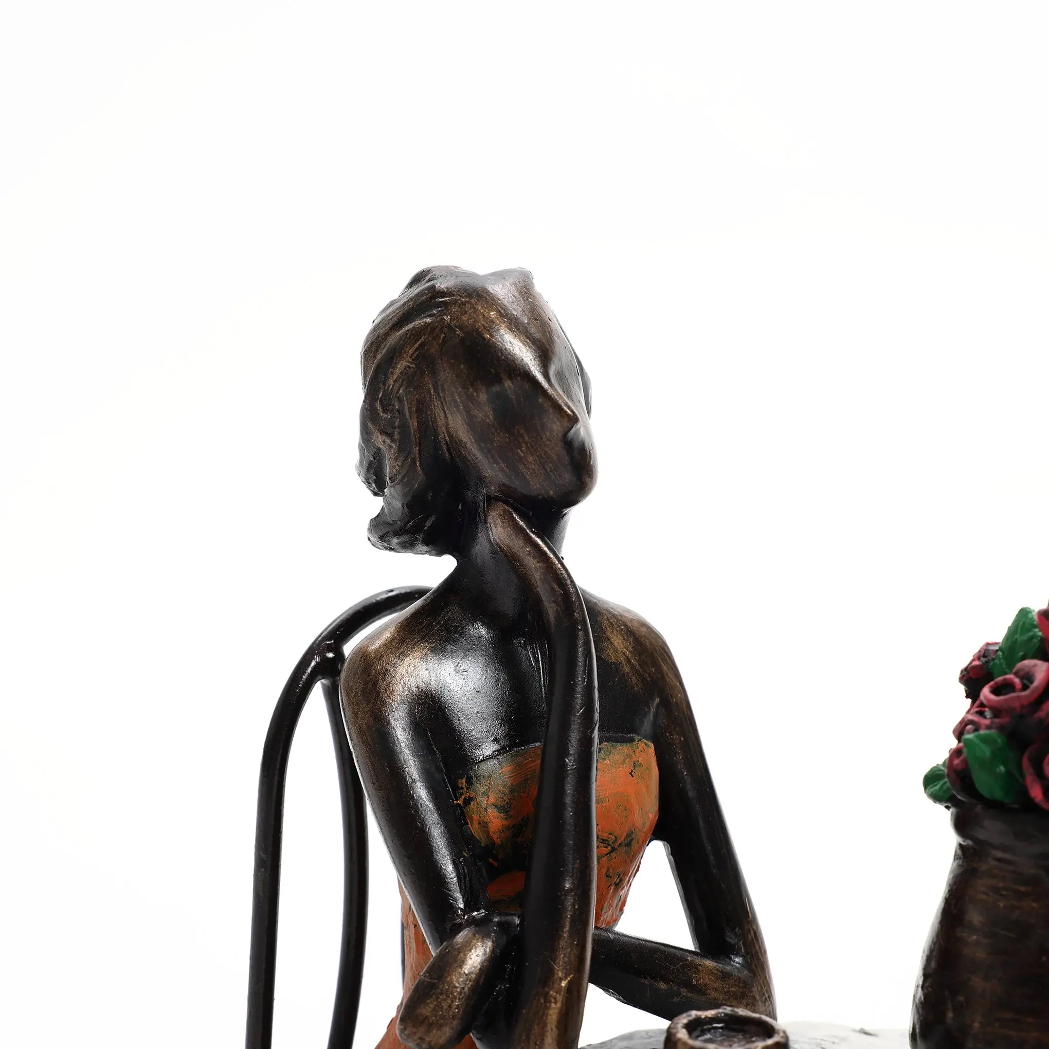 Bronze sculpture of a seated woman with head tilted back, wearing a strapless dress, captures romantic moments next to a vase of flowers.
