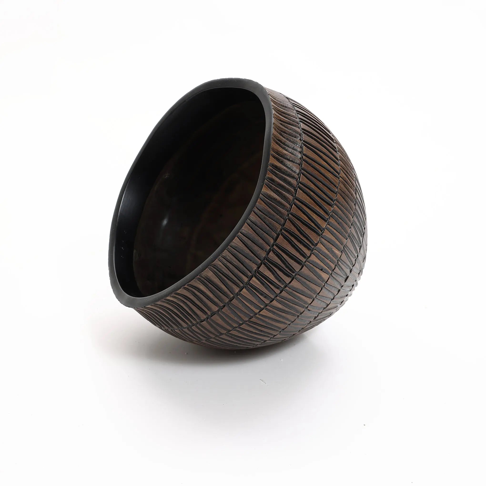 A LuxenHome small dark brown textured resin round planter, featuring intricate geometric grooves, is creatively tilted on its side against a white background.