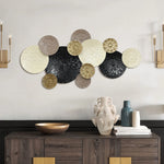 Nature-inspired artwork featuring interlocking circular shapes in various textures and shades of black, white, brown, and gold adorns the wall above a dark wood sideboard with decorative items, adding a touch of coastal abstract elegance.