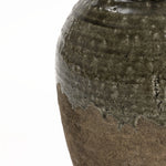 Close-up of a textured stoneware vase showcasing rustic charm, with a glossy green upper section and a matte brown lower section. The surface reveals natural imperfections and a wavy transition between colors, perfect for enhancing floral arrangements.