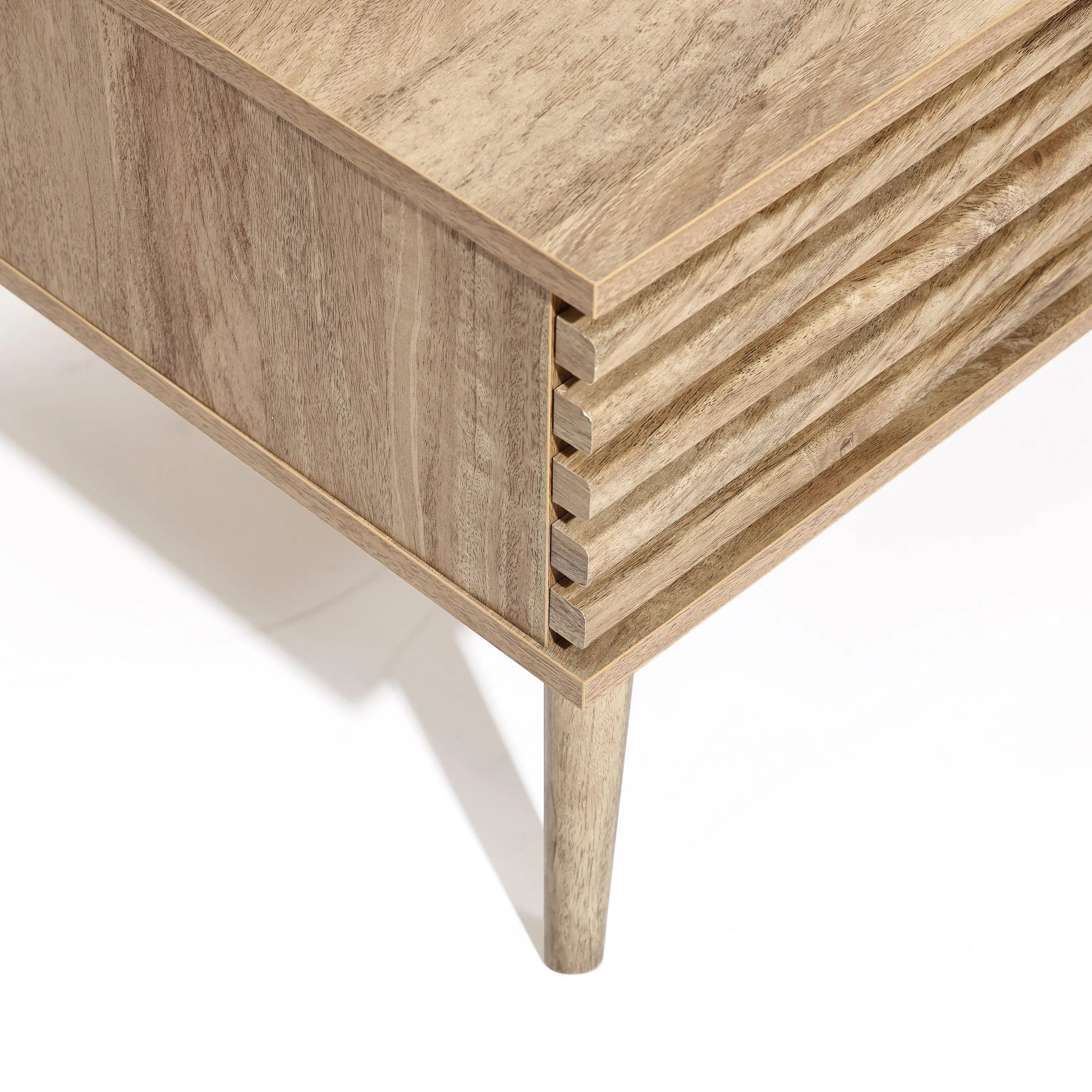 Close-up of a wooden coffee table corner with a minimalist design, featuring a ribbed texture on the side and tapered legs. This elegant piece includes dual-side storage, seamlessly blending form and function into your living space.
