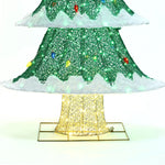 Close-up of a decorative Christmas tree with a lighted base, showcasing green foliage and white accents illuminated by vibrant LED lights, perfect for holiday decor.
