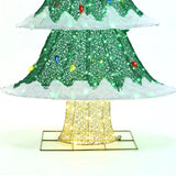 Close-up of a decorative Christmas tree with a lighted base, showcasing green foliage and white accents illuminated by vibrant LED lights, perfect for holiday decor.