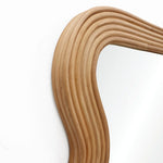 Curved rattan mirror frame with a modern vibe against a white wall.