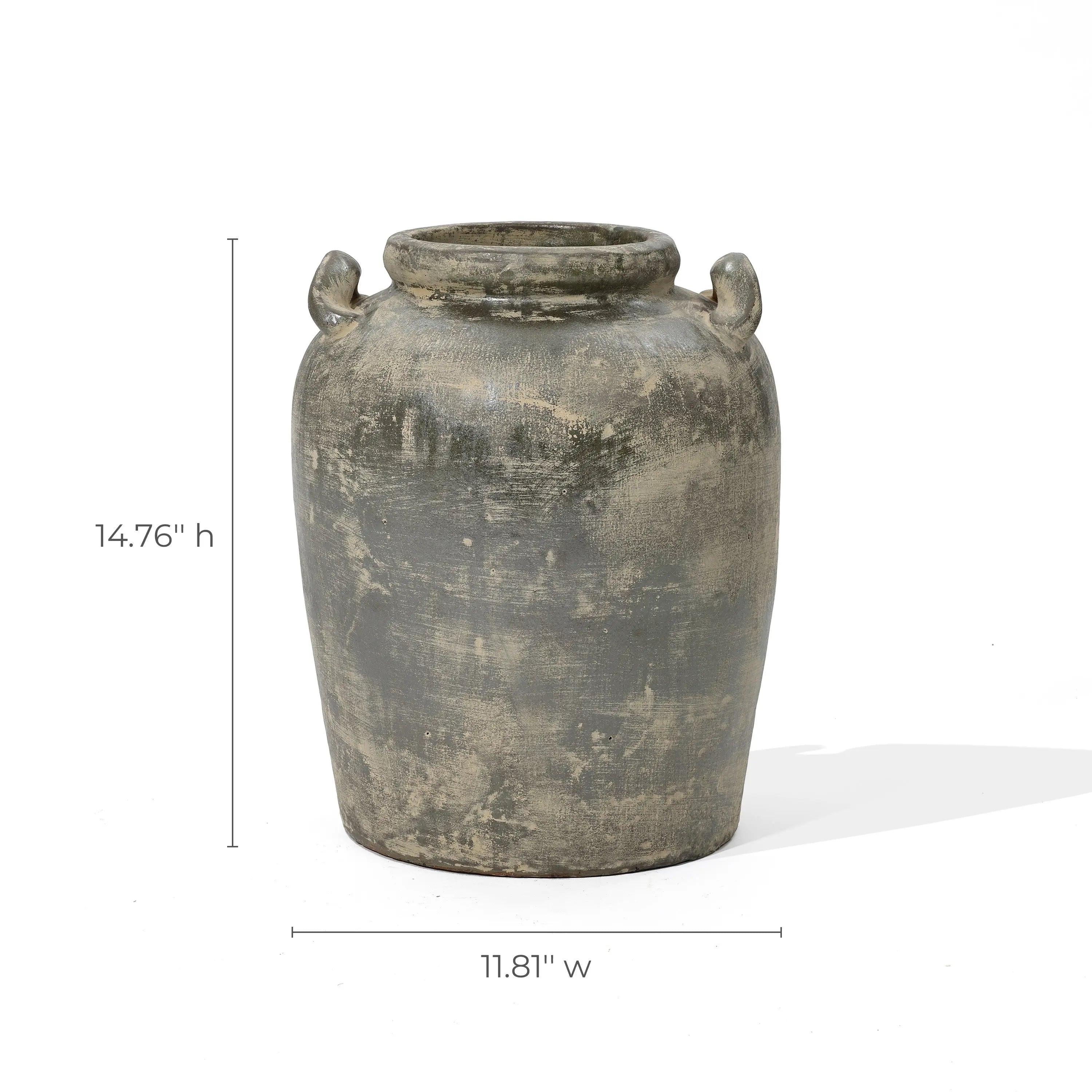 The Fou antique terracotta vase by LuxenHome is a weathered, cylindrical ceramic piece with a rustic texture, featuring two small handles near the rim. It measures 14.76 inches in height and 11.81 inches in width, embodying an artisanal charm and timeless elegance.