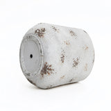 A used paint roller, embodying a vintage minimalist style, is covered in white and brown splatters against a plain white backdrop.