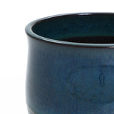 Close-up of a blue ceramic planter with a smooth surface and a slightly flared rim. The glaze has a textured, mottled appearance, making it an exquisite decorative piece for any space.