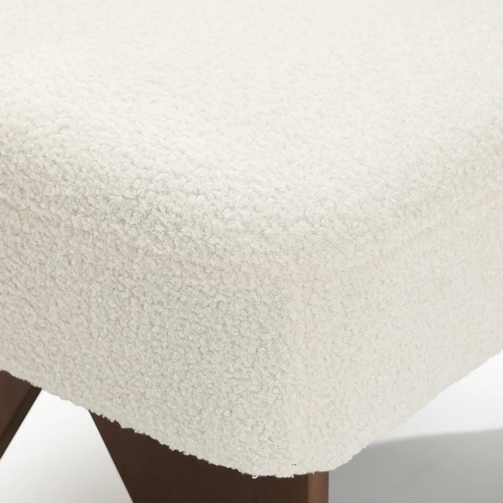 The LuxenHome Lorenzo boucle upholstered armless accent chair features a textured, soft wool-like white fabric on a cushioned seat with wooden angled legs, exuding mid-century allure.