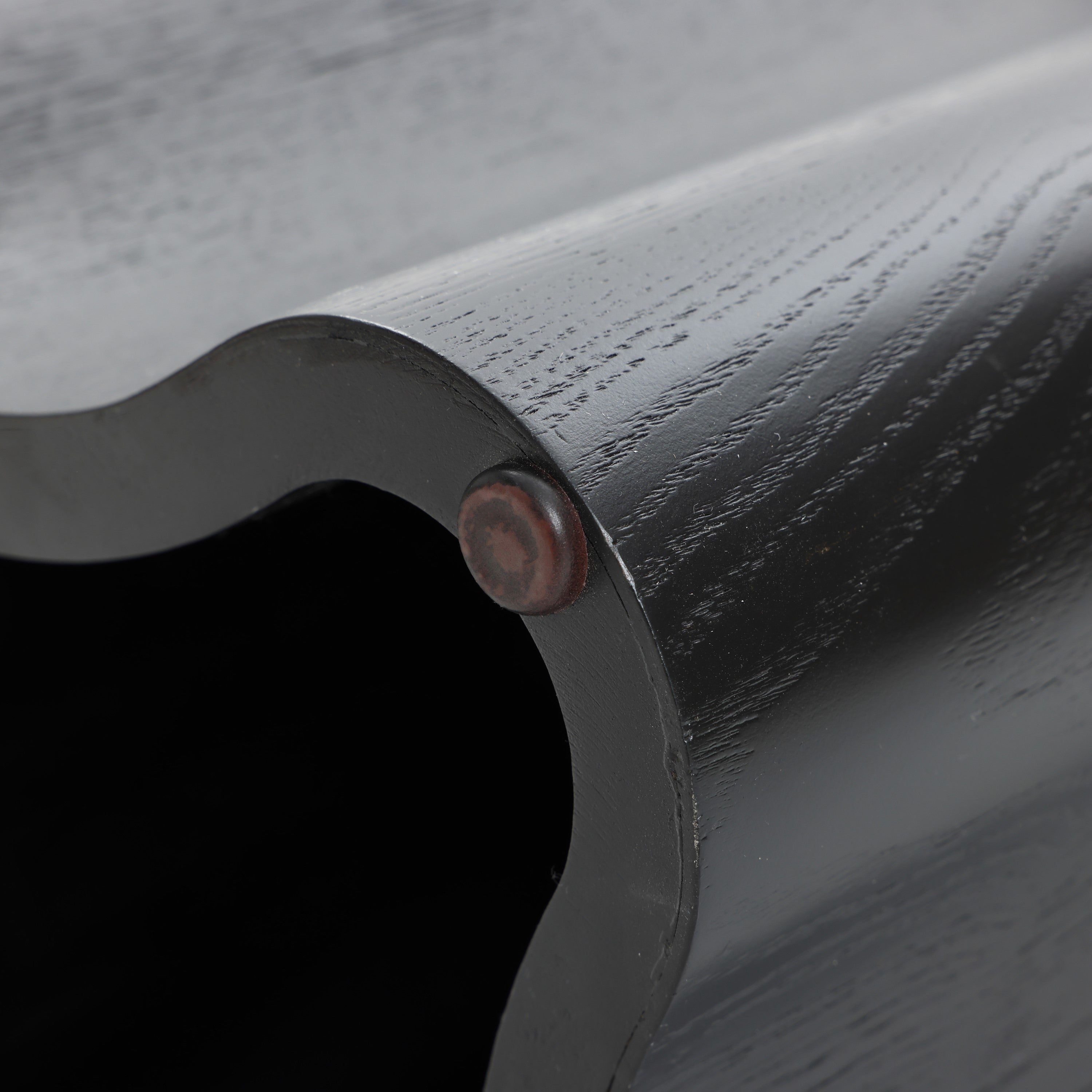 Close-up of a black cloverleaf shape crafted from premium MDF wood, showing visible grain and a round metal fastener at the edge.