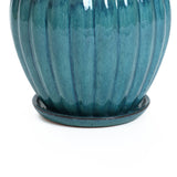 A ceramic decorative planter featuring a round, ribbed design with a navy blue glaze, complete with a matching saucer and drainage holes at the base.