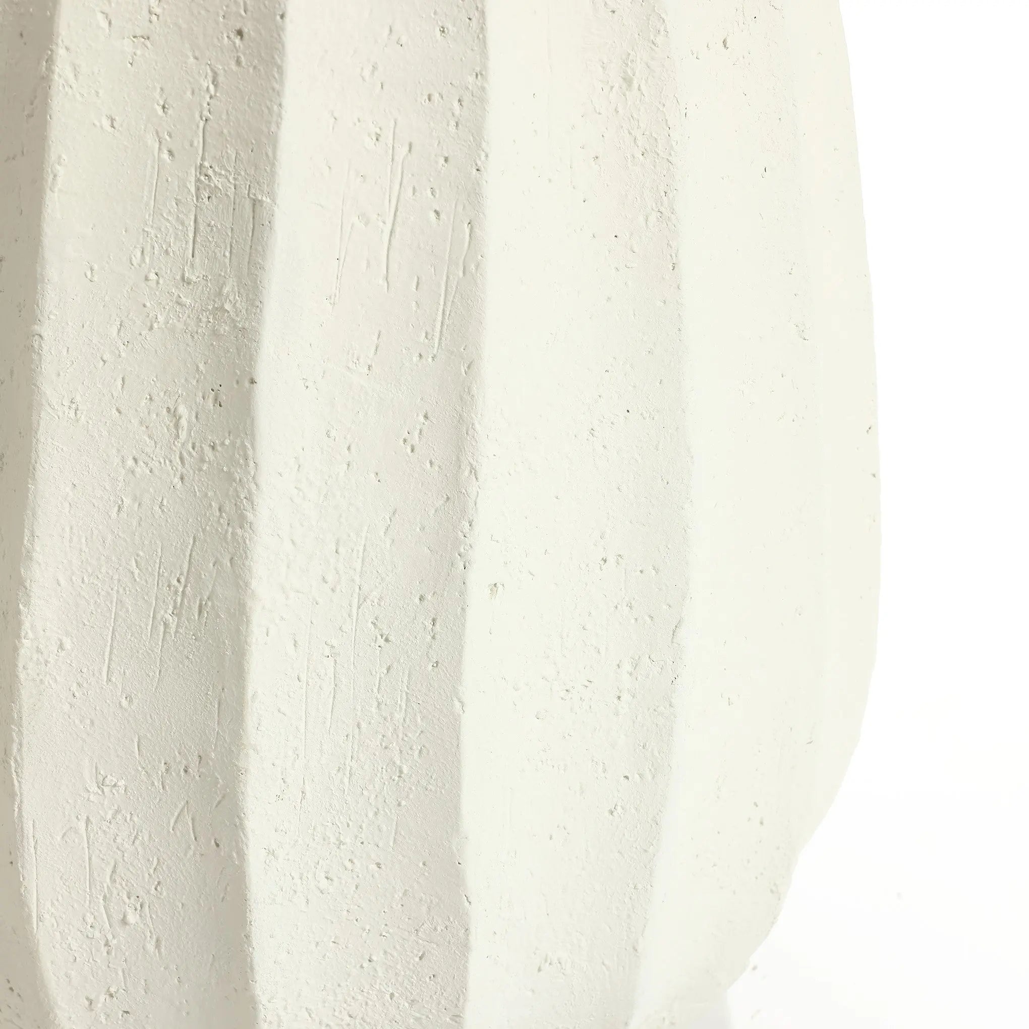 Close-up of a modern white vase with a textured surface, featuring vertical ridges and subtle scratches, perfect as an artistic centerpiece for minimalist home decor.