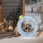 A large illuminated ornament with a snowflake design graces the snowy porch, surrounded by holiday decorations including lanterns, candles, a star decoration, and a decorative reindeer.