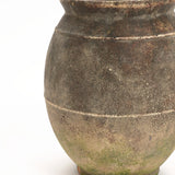 Close-up of an aged, large terracotta urn vase with a round body, a narrow top, and visible weathering and moss near the base. Perfect for both indoor and outdoor settings, its rustic charm adds character to any space.