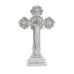 A decorative white crucifix, embodying the Christian faith, features an intricate design with a central figure of Jesus, elegantly standing on a rectangular base—perfect for religious occasions.