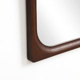 Elegant wall mirror with a rounded corner, featuring a carefully crafted rubberwood frame, perfect for enhancing any home decor. Beautifully mounted on a pristine white wall, it adds both style and function to your space.