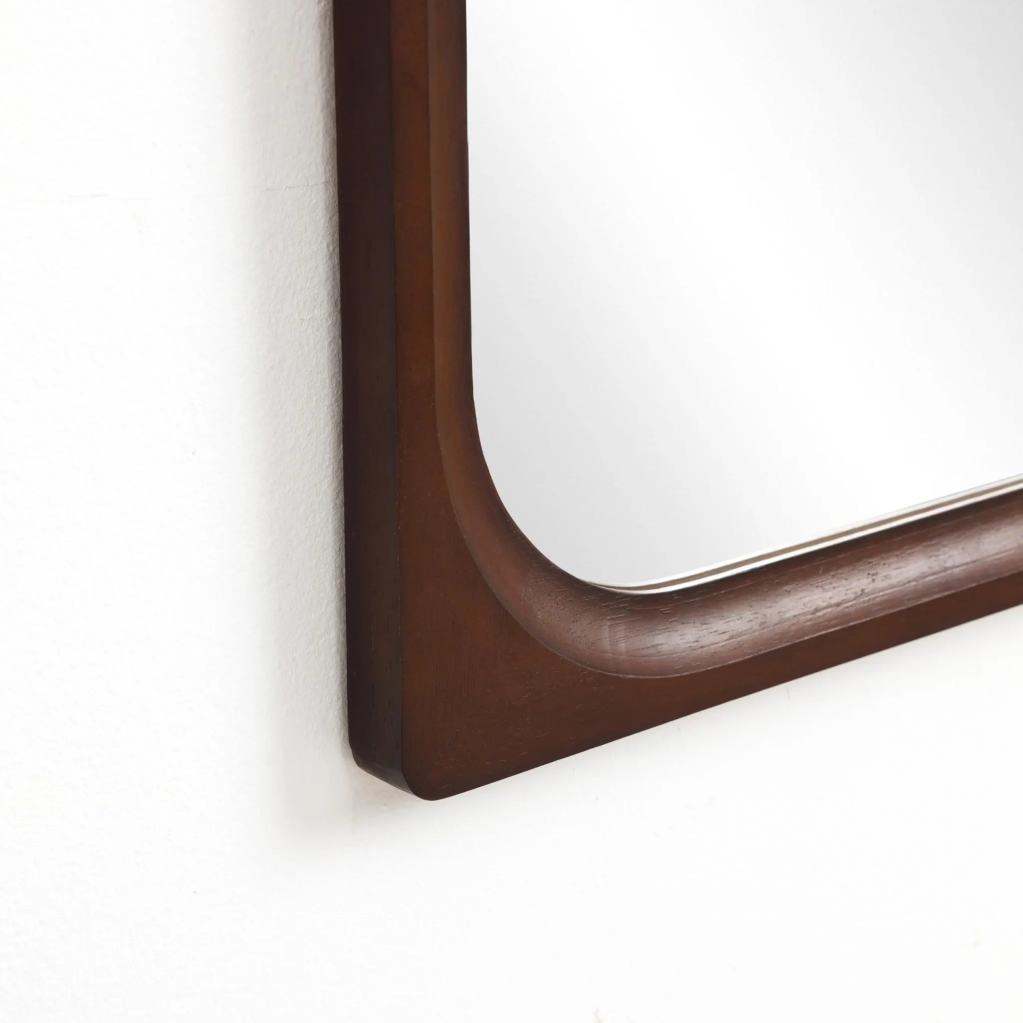 Elegant wall mirror with a rounded corner, featuring a carefully crafted rubberwood frame, perfect for enhancing any home decor. Beautifully mounted on a pristine white wall, it adds both style and function to your space.