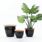 A decorative set of three black and tan planter pots, one showcasing a tall artificial Monstera plant, neatly arranged against a plain white background. Perfect for both indoor and outdoor use.