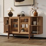 A cozy, well-lit room with wooden flooring features the LuxenHome Miko sideboard server cabinet with solid wood legs. Open shelves display pottery and dishes, while a table lamp and dried flowers in a vase sit on top. A framed abstract painting hangs above completing the mid-century modernist look.