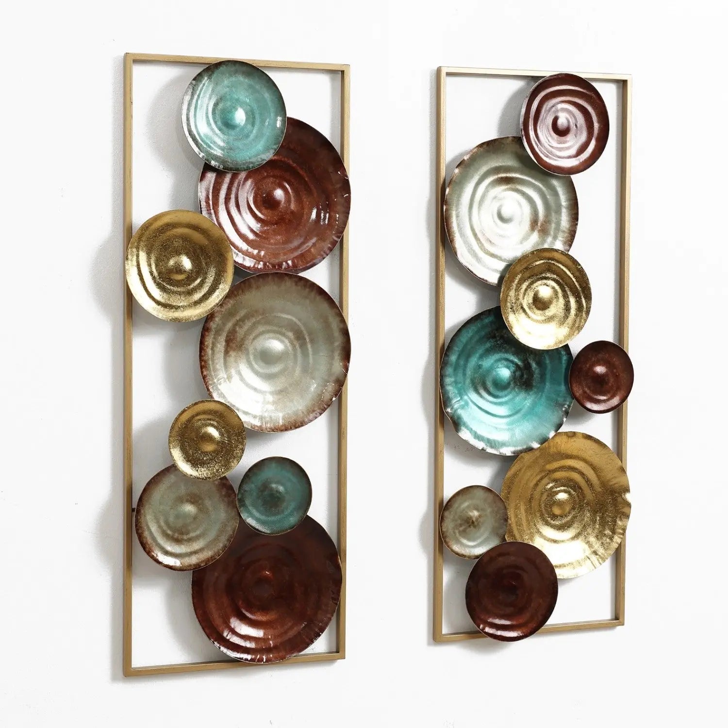 Two vertical decorative wall sculptures feature circular, textured discs in brown, teal, and gold tones, arranged within rectangular gold frames against a white background.