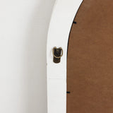 Close-up of the back of a framed picture, similar to an arched rectangular mirror, with a bronze hanging hook attached to a white edge and brown backing. Its perfect for adding elegance to any home decoration scheme next to a pristine white wall.
