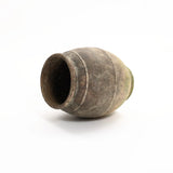 A rustic, aged terracotta urn vase gently rests on its side against a plain white background, exuding timeless charm.