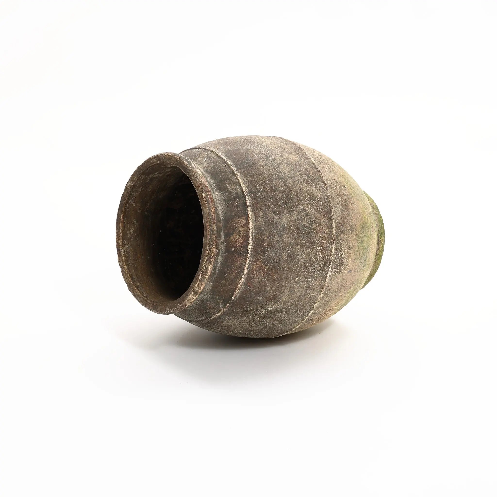 A rustic, aged terracotta urn vase gently rests on its side against a plain white background, exuding timeless charm.