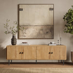 Wooden minimalist TV stand with black handles stands against a beige wall. Above it hangs a painting in neutral tones.