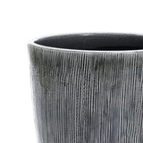 Close-up of the Sea gray ripples glazed tall ceramic planter by LuxenHome, 17 high, with vertical grooves and a shiny dark gray finish against a light gray background.