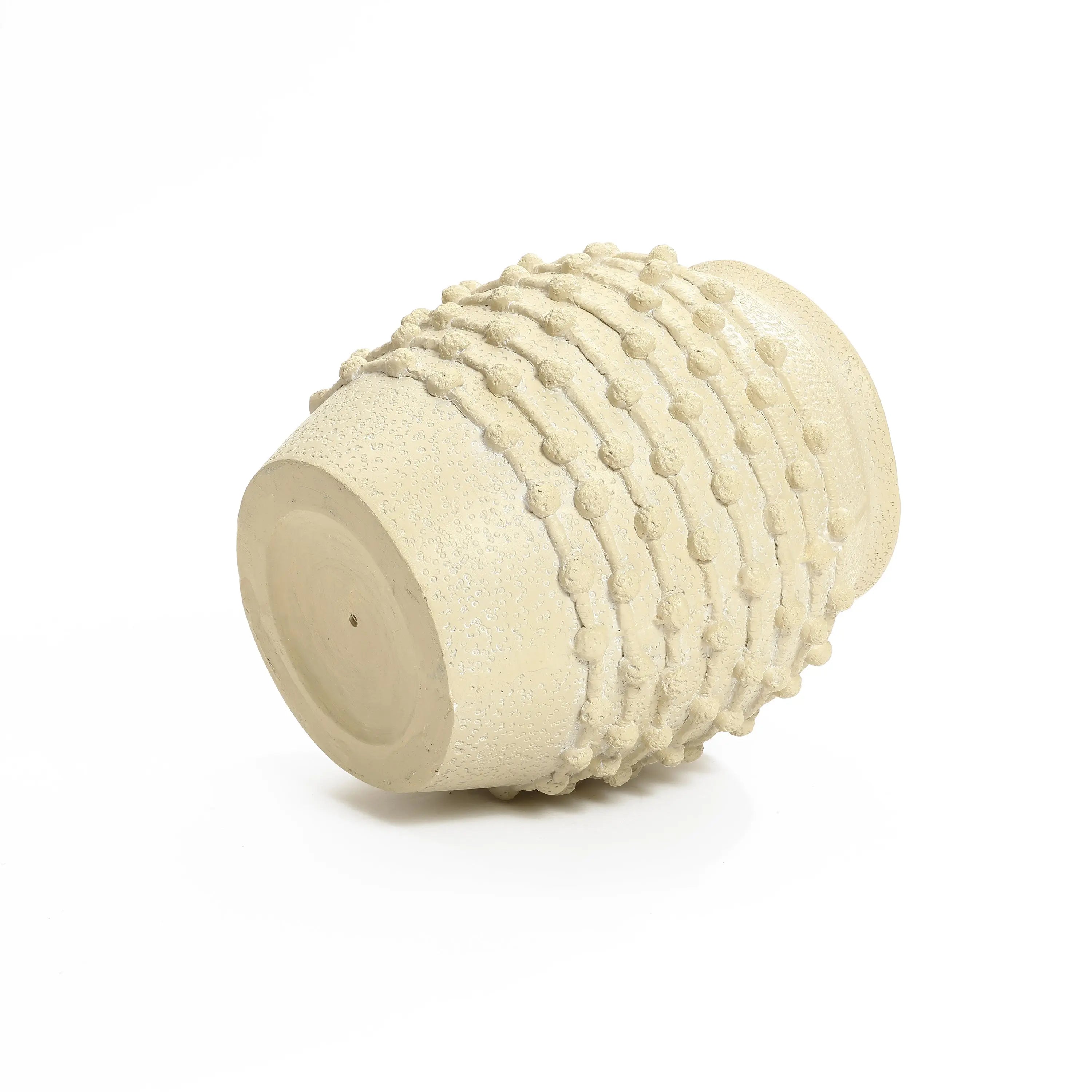 A beige ceramic vase with a textured, bumpy surface lies on its side against a plain white background, showcasing exquisite boho planter vibes.