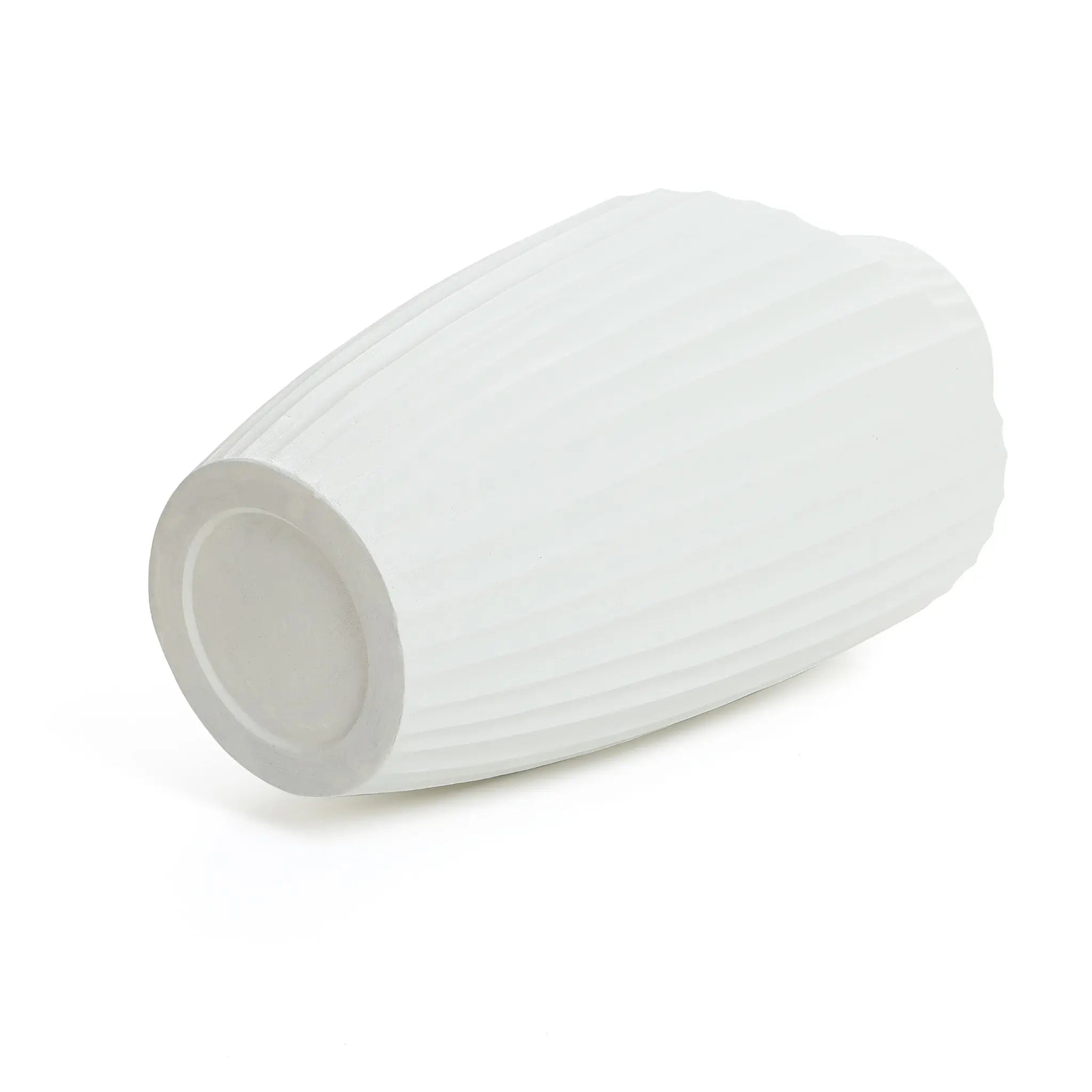 A modern abstract sculpture vase, white and ribbed, lies on its side with a narrow opening and flat base, showcasing its potential as a striking piece for contemporary home decor against a plain white backdrop.