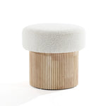 The LuxenHome Mina boucle and wood storage ottoman features a textured white cushioned seat with a cylindrical base of vertical wooden slats. Its modern, minimalist design blends neutral colors and natural materials, adding elegance to any space.