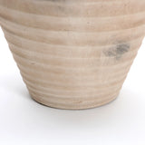 A LuxenHome Rustic beige ribbed terracotta urn vase, measuring 13.2 in height, sits on a white surface. Its handcrafted details and slight discolorations add rustic charm akin to a terracotta vase.