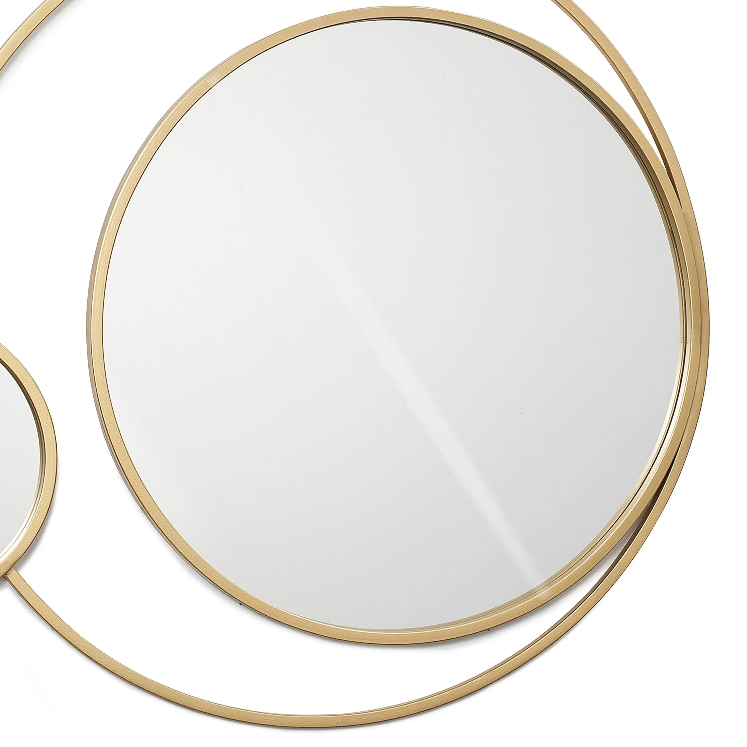 Two circular wall mirrors with thin golden frames elegantly intersect on a white background, embodying modern elegance.