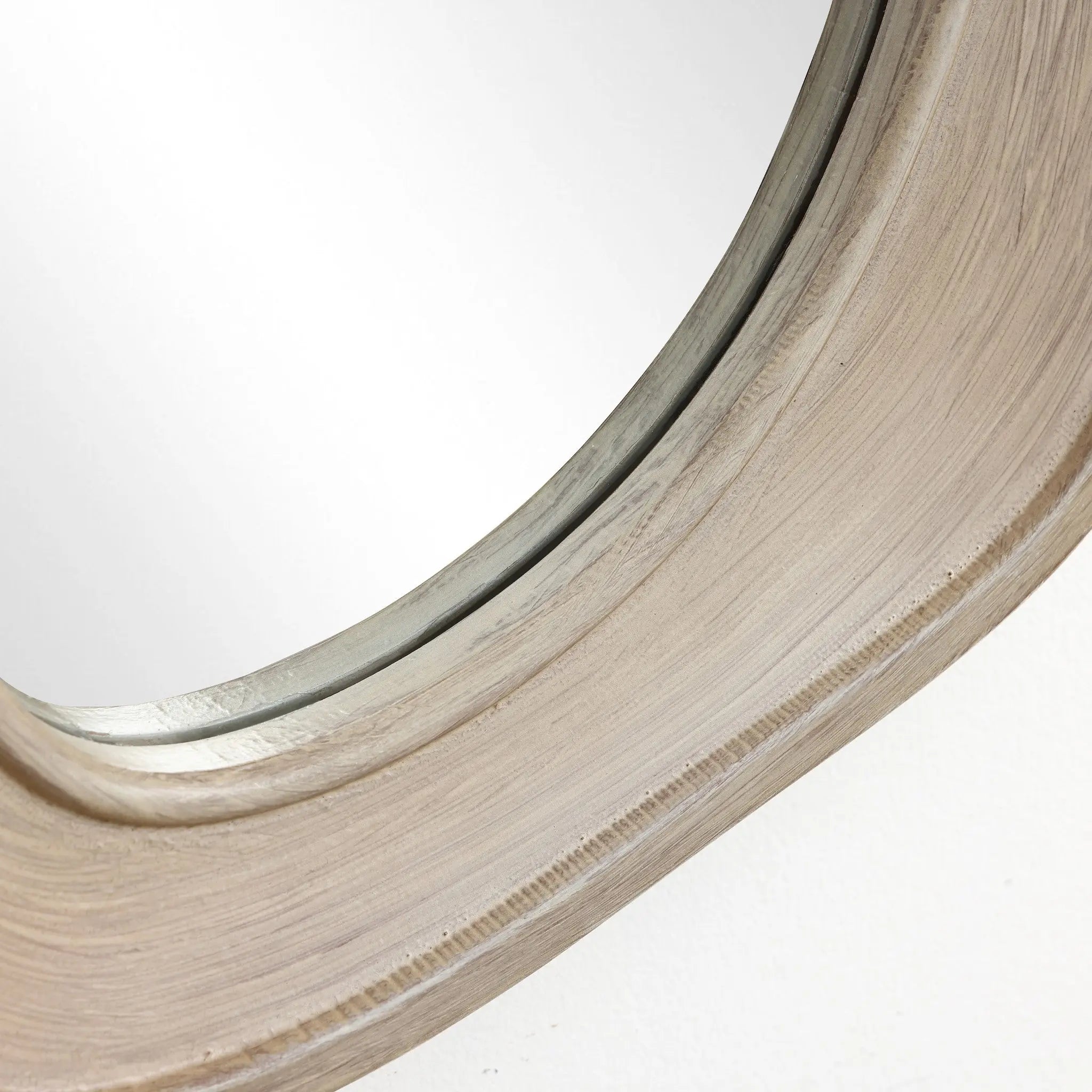 Close-up of an oval, irregularly shaped wall mirror partially reflecting light. The wood frame has a smooth, natural finish, perfectly complementing modern home decor.