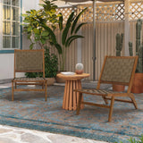 Two woven chairs and a small table made of Acacia wood hold a potted cactus on a blue rug. The background features lush potted plants and a charming wooden lattice fence, making it the perfect outdoor furniture setup for relaxation.