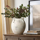 An 11 tall multi-gray and white terracotta vase with handles by LuxenHome sits on a wooden cabinet, holding lush greenery with red-tipped leaves. Stacked books are beside it, and a framed picture hangs on the wall behind.