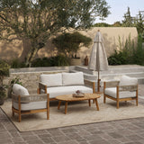 Outdoor patio with a wooden coffee table, Rope Sides Armchair, loveseat with weather-resistant cushions, a large umbrella, and surrounding greenery on a tiled floor.
