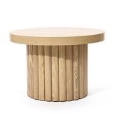 This round wooden table with a cylindrical base featuring vertical slats boasts a modern design and oak finish, making it an ideal coffee table centerpiece.