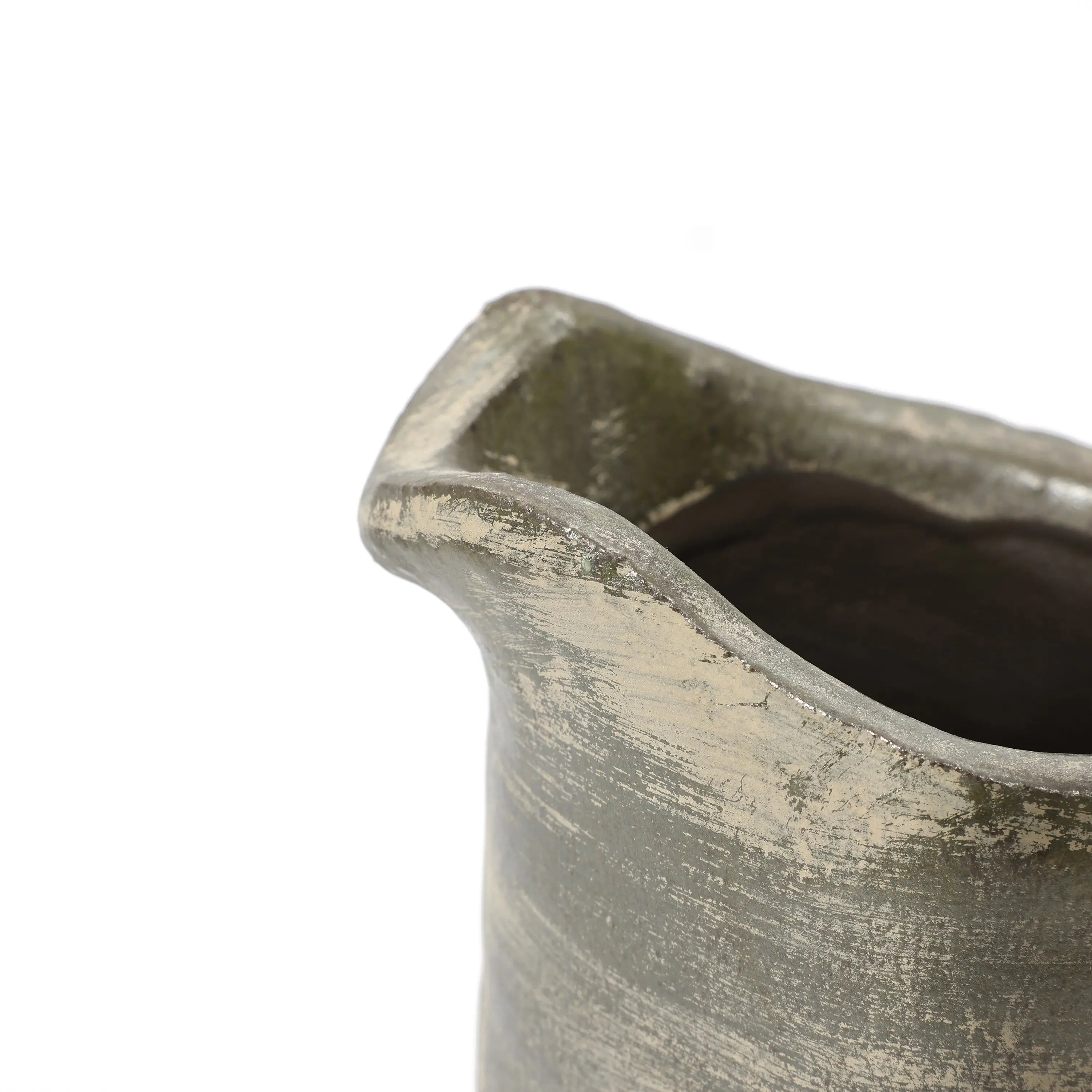 A close-up of a rustic, handmade clay pitcher vase showcases its textured, uneven rim and dark, earthy glaze, reflecting artisanal craftsmanship.