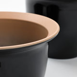 Close-up of a black planter pot with a beige rim, artfully overlapping another in the background, part of a decorative set perfect for indoor and outdoor use.