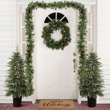 White front door is decor with wreath,garland red ornaments, flanked by 2 potted artificial trees ,doormat reading Happy Holidays.
