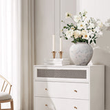 A white dresser with round cement flower vase filled with white blooms in a bright minimal room with.