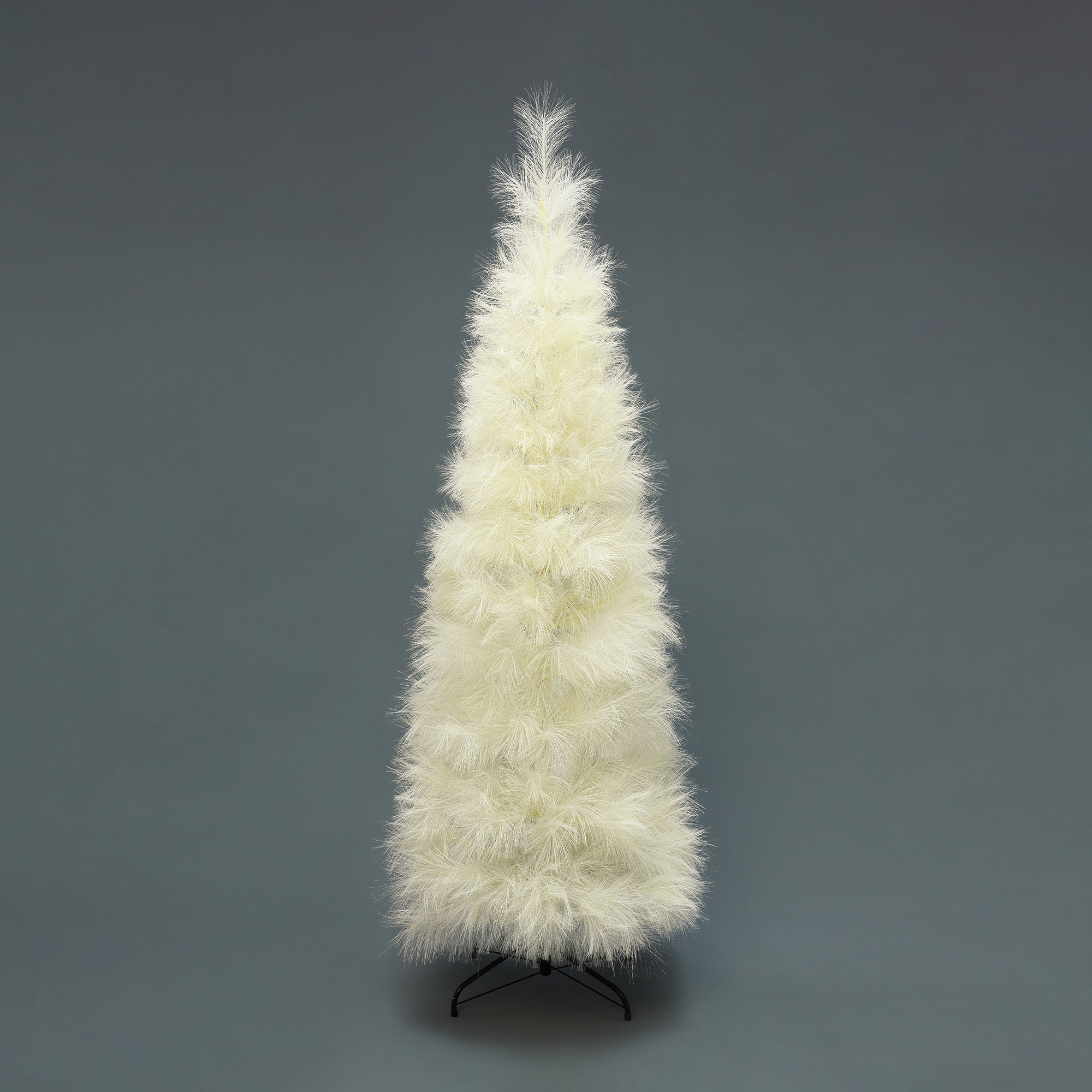 White artificial christmas tree with fluffy, feather-like branches stands on  black metal stand against plain gray background.