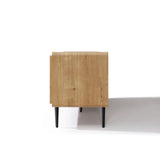 Side view of a wood TV stand with black legs, placed on a white surface with a shadow cast to the right.