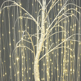 Close-up of artificial willow tree with thin branches, wrapped in small, warm white string lights against gray background.