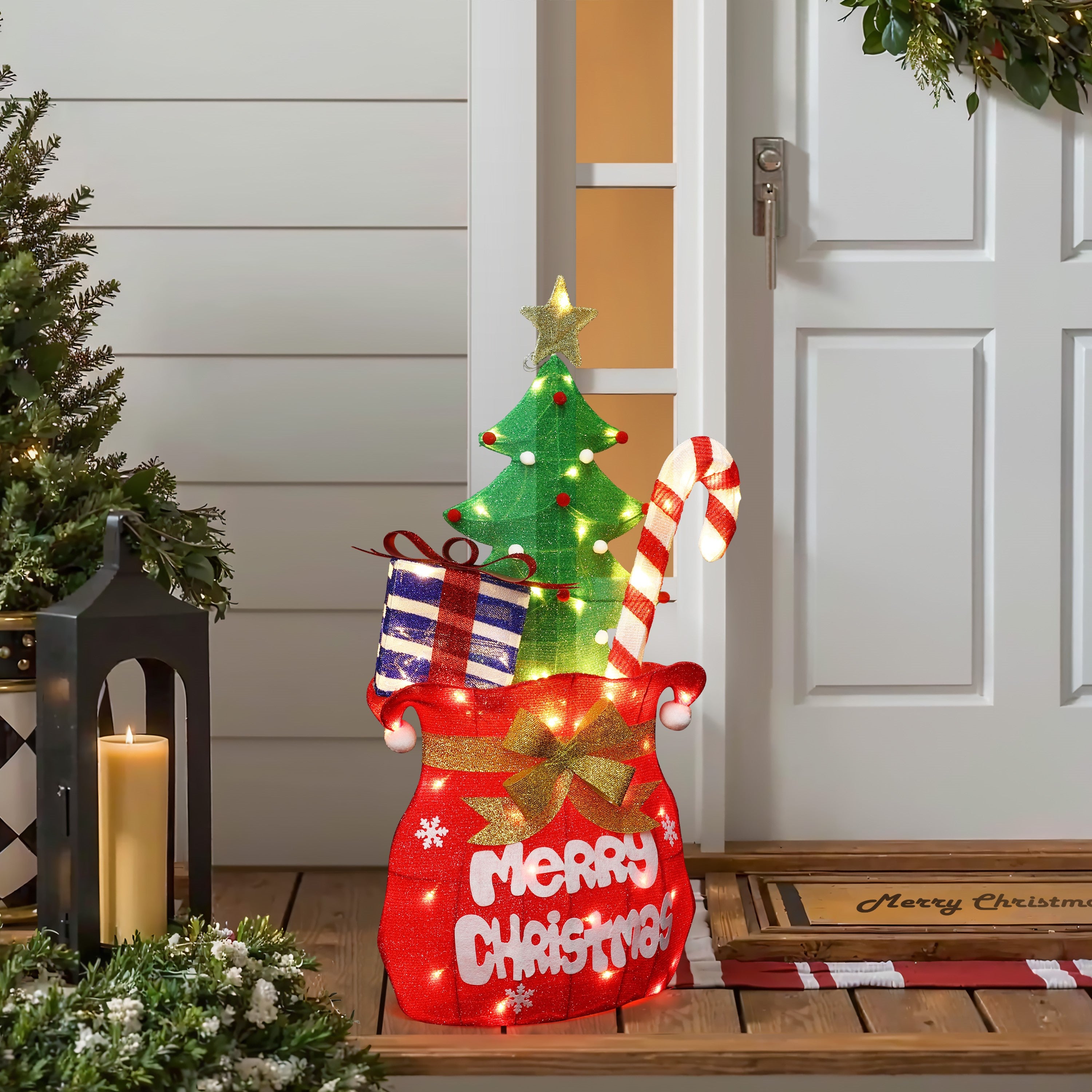 Festive outdoor display shaped like stocking with gifts,candy cane, tree stands by front door.