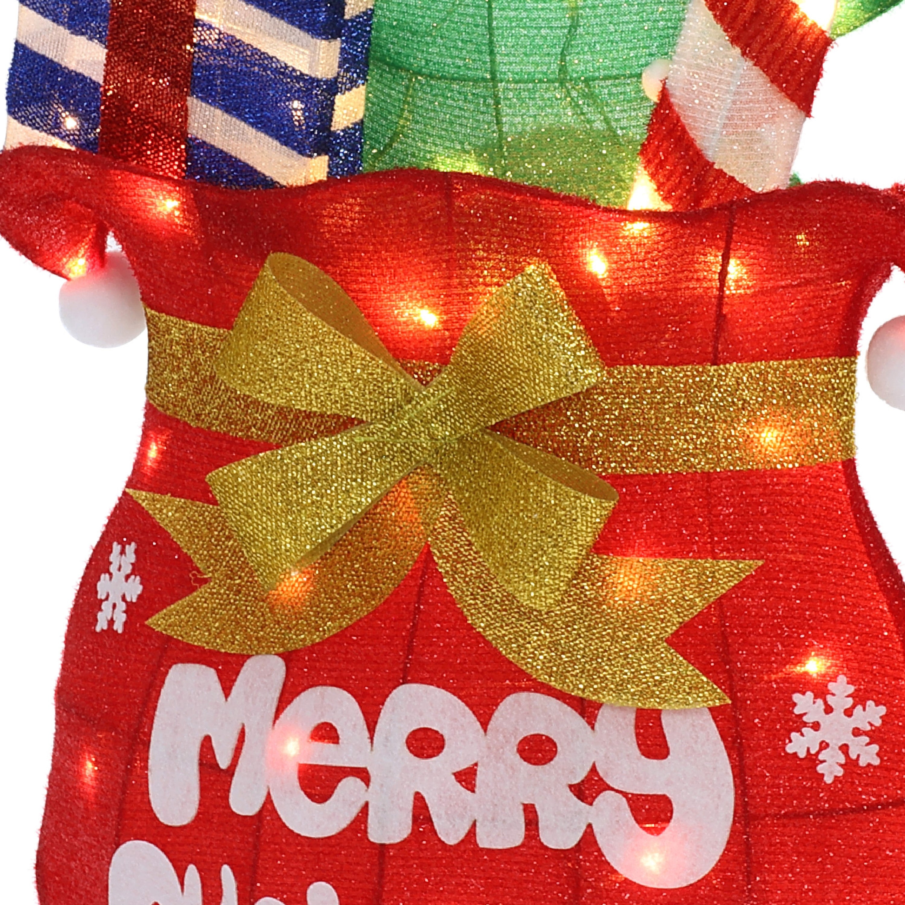 Close-up of red Holiday Decor, a gold bow, white snowflakes, the word “Merry” partially visible, all illuminated.