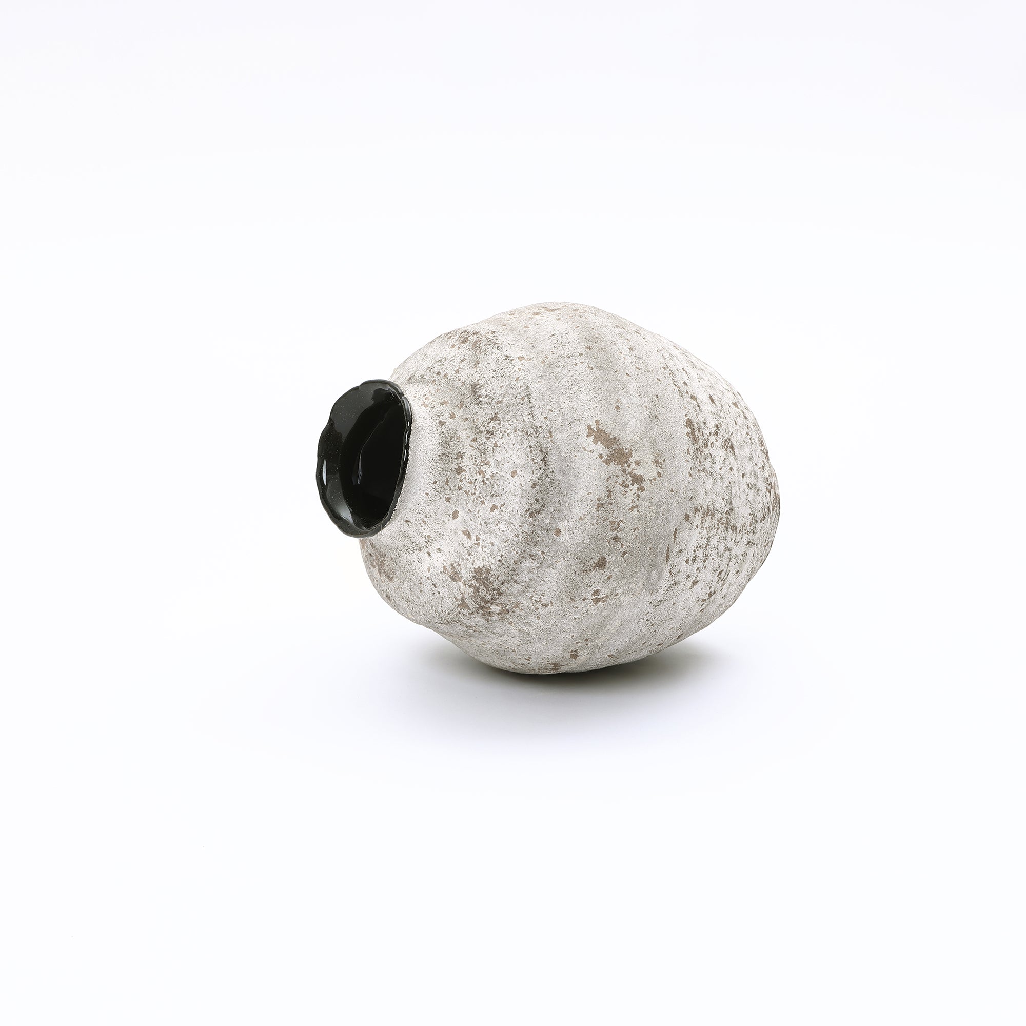 Irregularly cement vase with a rough, grayish-white surface and a glossy black opening.